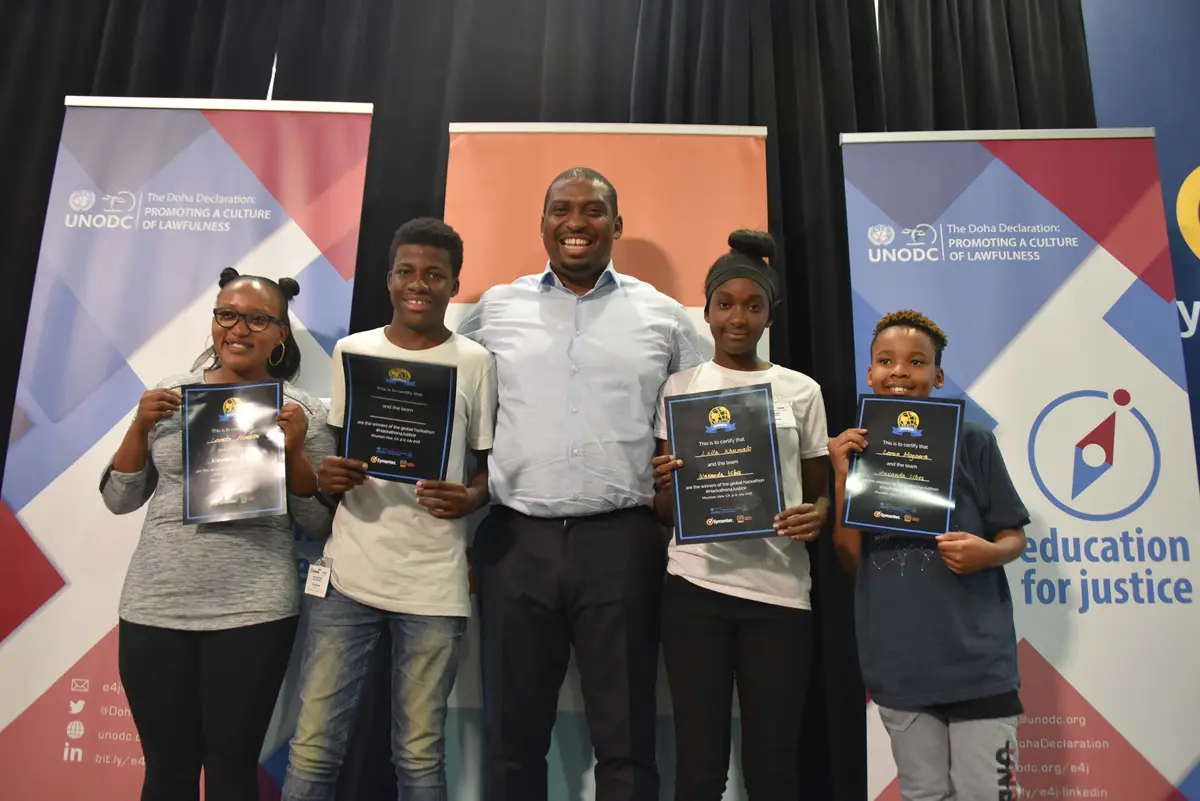 Young participants holding certificates in front of banners about education for justice